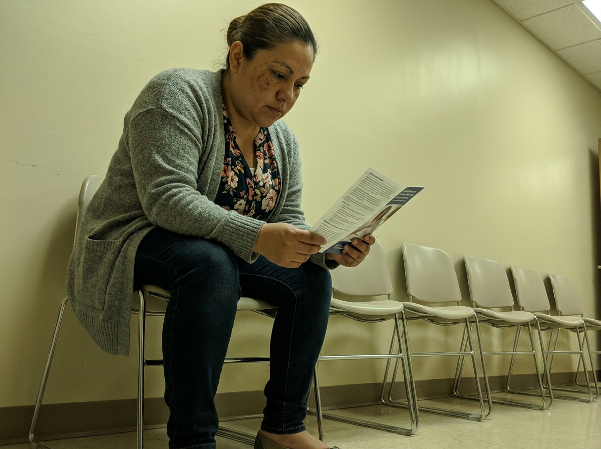 A woman reading a pamphlet while waiting in a clinic waiting room